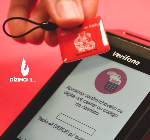 Pessoa aproximando um chaveiro na maquininha do dízimo